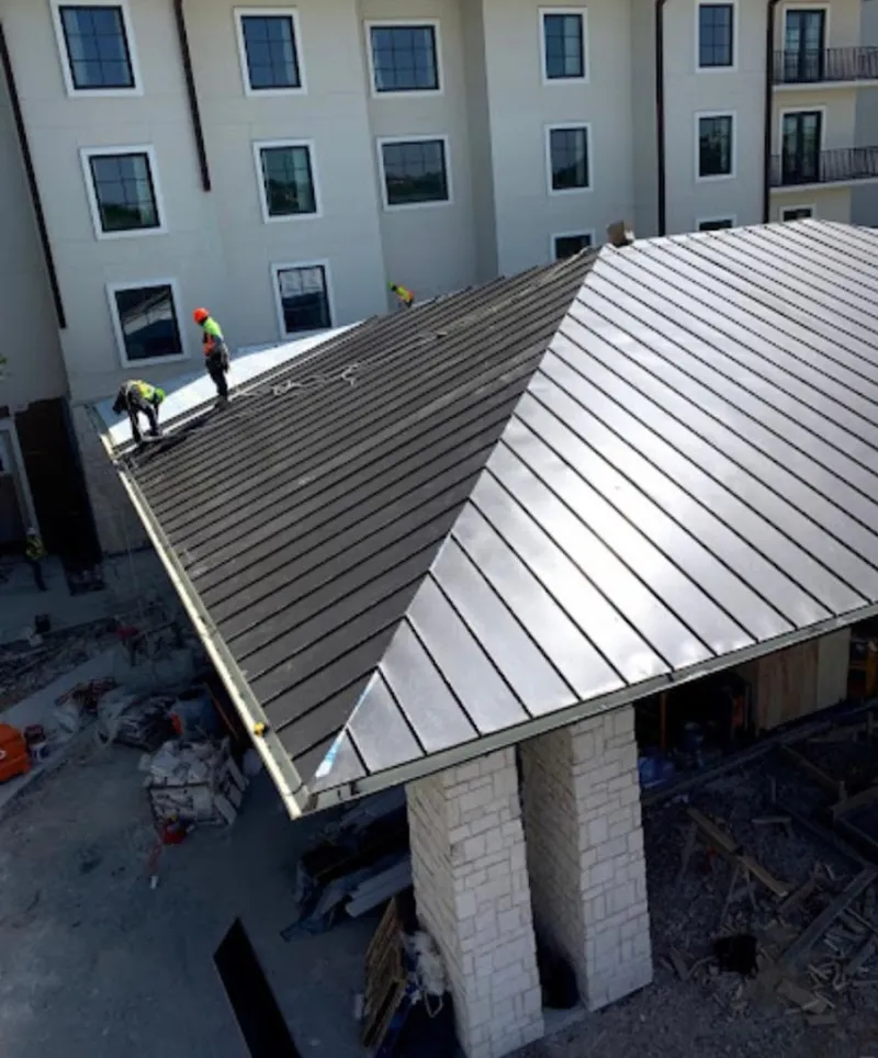 Crew installing standing seam metal roof panels on a commercial project in Lawton